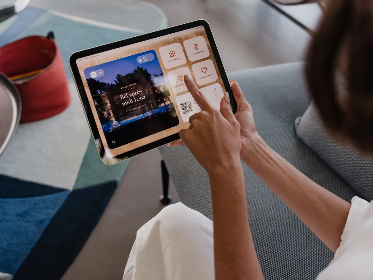 Une voyageuse consulte le guide ByOhana sur la tablette, dans le salon d’une villa